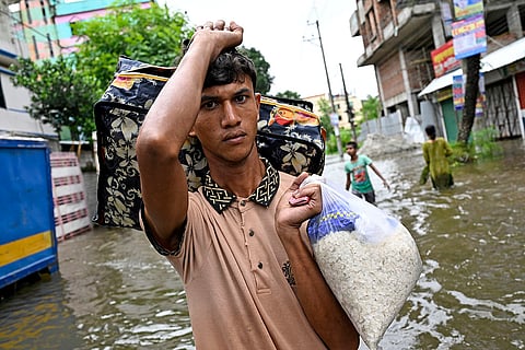 Bangladesh Floods: A man walks with belongings to a relief shelter